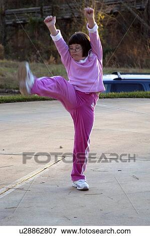 Little girl with Down syndrome practicing gymnastics in a parking lot. View Large Photo Image Stock Photo - Little girl with Down syndrome practicing gymnastics in a parking lot.. Fotosearch