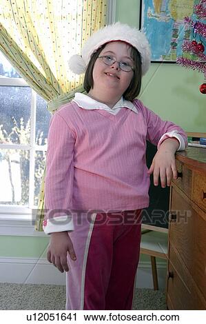 Little girl with Down syndrome wearing a white hat, standing by a desk and smiling. View Large Photo Image Stock Image - Little girl with Down syndrome wearing a white hat, standing by a desk and smiling.. Fotosearch
