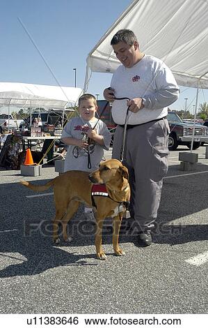 Stock Photograph - Man teaches young boy about service dogs. Fotosearch