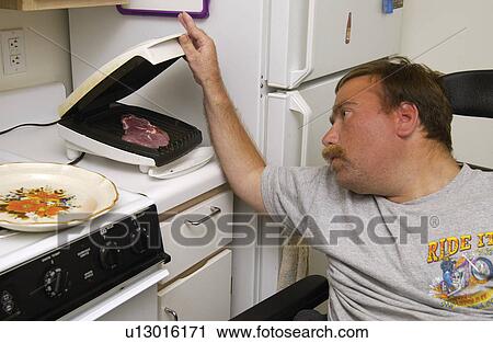 Man with a disability cooking his dinner in his kitchen, in his own apartment. View Large Photo Image Stock Image - Man with a disability cooking his dinner in his kitchen, in his own apartment.. Fotosearch