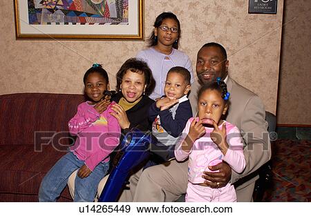 Stock Photo - Man with a disability, utilizing a wheelchair for mobility, posing for a picture with his wife and four children.. Fotosearch