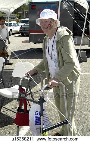 Stock Image - Woman with face paint uses walker at community event. Fotosearch