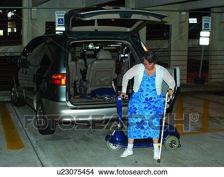 Picture - Woman with muscular dystrophy preparing to transfer her motorized scooter to her van. Her ability to transfer the scooter into her van has greatly increased her mobility and independence.. Fotosearch
