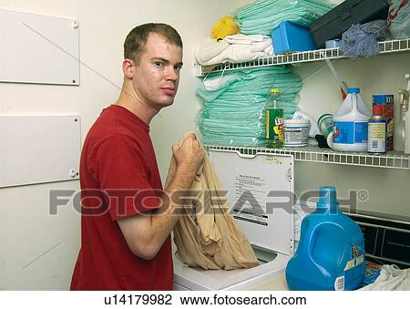 Young man with a disability doing his laundry in his home. View Large Photo Image Stock Image - Young man with a disability doing his laundry in his home.. Fotosearch