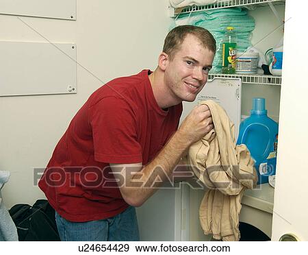 Young man with a disability doing his laundry in his home. View Large Photo Image Stock Photo - Young man with a disability doing his laundry in his home.. Fotosearch