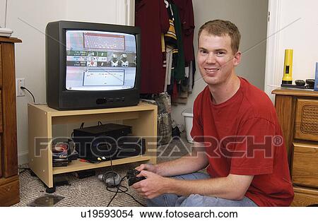 Picture - Young man with disabilities playing video games in his room.. Fotosearch