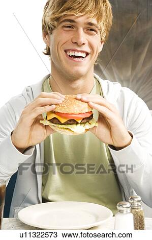 ティーンエージャーの少年 食べること A 大きい ハンバーガー 中に A 食事客 ストックイメージ U Fotosearch