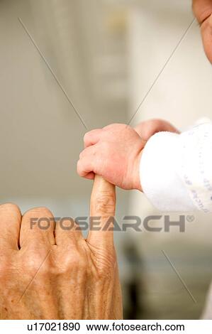 Stock Image - A baby's hand holding their grandparent's finger. Fotosearch