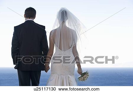A bride and groom holding hands View Large Photo Image Stock Image - A bride and groom holding hands. Fotosearch