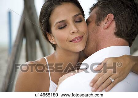 A bride and groom kissing on a beach View Large Photo Image Stock Image - A bride and groom kissing on a beach. Fotosearch