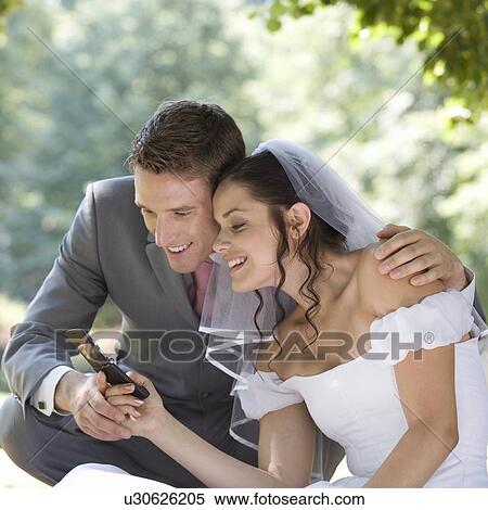 A bride and groom using a mobile phone View Large Photo Image Stock Photography - A bride and groom using a mobile phone. Fotosearch