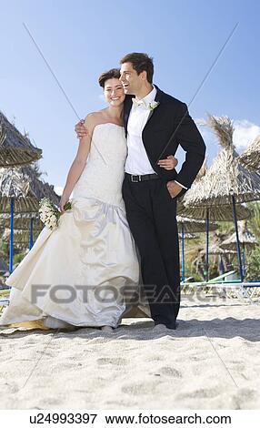 Stock Photo - A bride and groom walking on a beach. Fotosearch