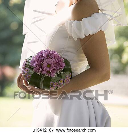 Stock Photo - A bride holding a bouquet. Fotosearch