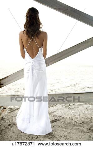 Stock Image - A bride standing on a beach. Fotosearch