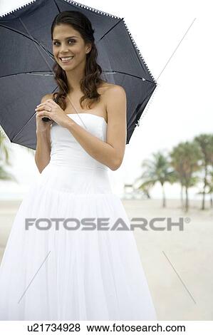 Stock Photo - A bride standing under an umbrella. Fotosearch