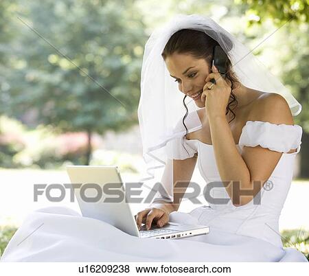 A bride using a laptop and mobile phone View Large Photo Image Stock Photo - A bride using a laptop and mobile phone. Fotosearch