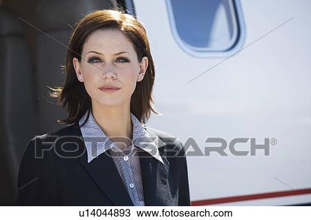 Stock Image - A business woman standing by a plane. Fotosearch