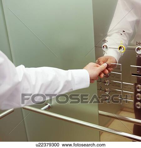 Stock Image - A businessman calling a lift. Fotosearch
