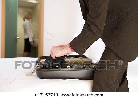 Stock Image - A businessman packing a suitcase. Fotosearch