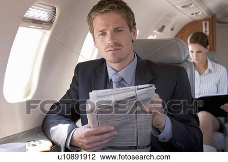Stock Image - A businessman reading the paper on a plane. Fotosearch
