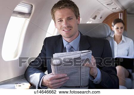 A businessman reading the paper on a plane View Large Photo Image Stock Image - A businessman reading the paper on a plane. Fotosearch
