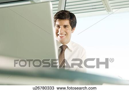 Stock Image - A businessman sitting at his desk. Fotosearch