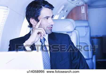 Stock Photography - A businessman sitting on a plane. Fotosearch