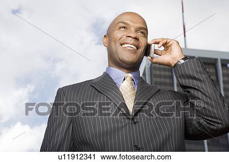 Stock Image - A businessman talking on a mobile phone. Fotosearch
