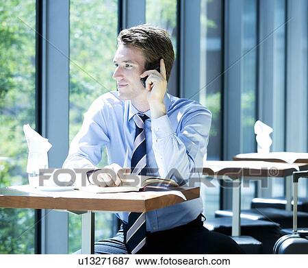 Stock Photo - A businessman talking on a mobile phone whilst waiting to travel. Fotosearch