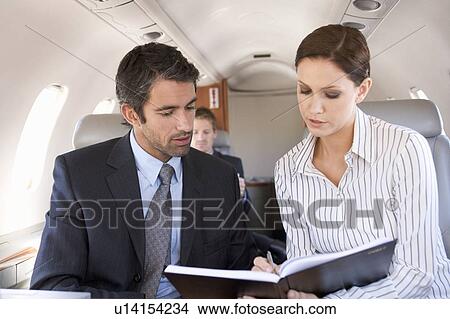 Picture - A businessman talking to his PA on a plane. Fotosearch