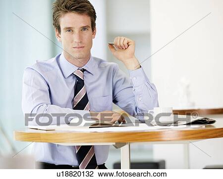 Stock Image - A businessman waiting in a hotel lobby. Fotosearch