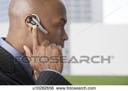 A businessman wearing a bluetooth headset View Large Photo Image Stock Photograph - A businessman wearing a bluetooth headset. Fotosearch