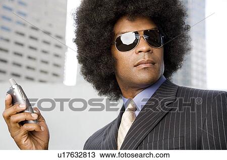 Stock Image - A businessman with an Afro hairstyle talking on a mobile phone. Fotosearch