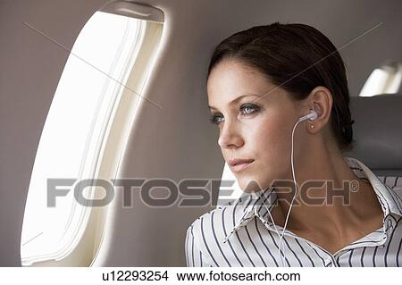 A businesswoman listening to music on a flight View Large Photo Image Picture - A businesswoman listening to music on a flight. Fotosearch