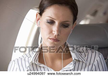 A businesswoman listening to music on a flight View Large Photo Image Stock Photo - A businesswoman listening to music on a flight. Fotosearch