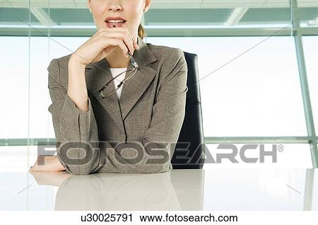 Stock Image - A businesswoman sitting at a table. Fotosearch