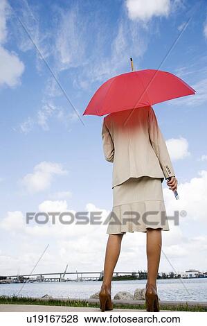 A businesswoman standing underneath an umbrella holding a mobile phone View Large Photo Image Stock Photo - A businesswoman standing underneath an umbrella holding a mobile phone. Fotosearch