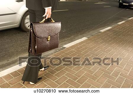 A businesswoman walking on a pavement View Large Photo Image Stock Image - A businesswoman walking on a pavement. Fotosearch