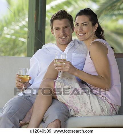 Stock Photo - A couple drinking wine on a swing. Fotosearch