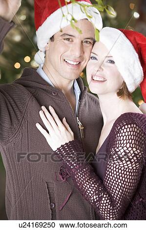 Stock Image - A couple kissing beneath the mistletoe. Fotosearch