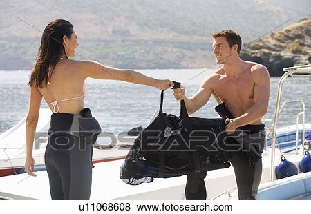 Stock Photo - A couple preparing to scuba dive. Fotosearch