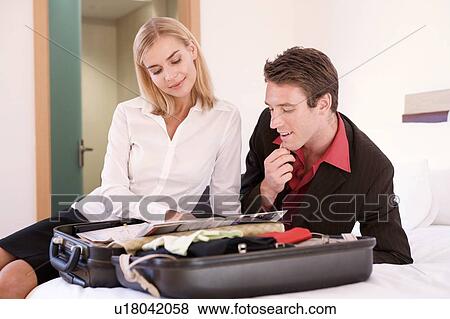 Stock Photo - A couple reading a brochure on a open suitcase. Fotosearch