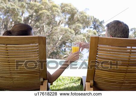 Stock Photo - A couple sitting in sun loungers. Fotosearch