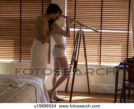Picture - A couple spying through a telescope. Fotosearch
