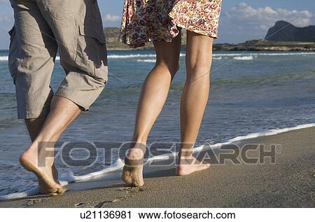 Stock Image - A couple walking along a beach. Fotosearch