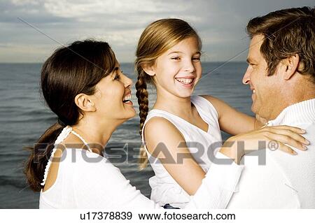 Stock Photo - A couple with their daughter on a beach. Fotosearch