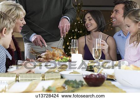 Picture - A family sitting down for Christmas dinner. Fotosearch