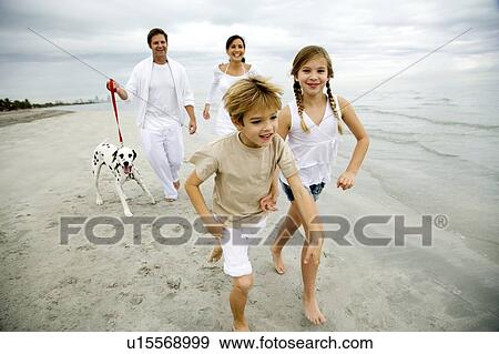 Stock Photo - A family walking the dog on a beach. Fotosearch