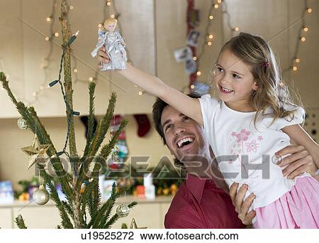 A father lifting his daughter to place the fairy on top of the Christmas tree View Large Photo Image Stock Image - A father lifting his daughter to place the fairy on top of the Christmas tree. Fotosearch