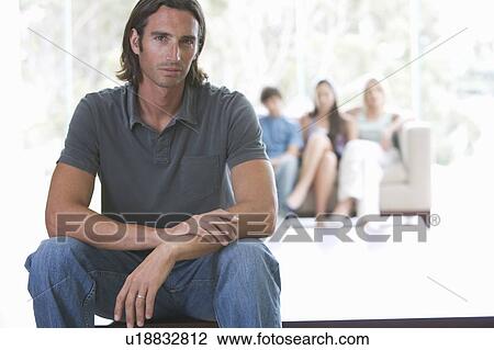 A father sitting on a coffee table with his family sitting in a sofa View Large Photo Image Stock Image - A father sitting on a coffee table with his family sitting in a sofa. Fotosearch